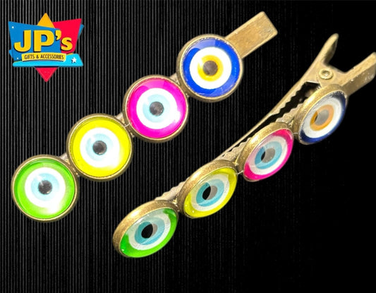 Four colorful evil eye hair clips in green, yellow, pink, and blue with matching metal clip versions displayed on black background.
