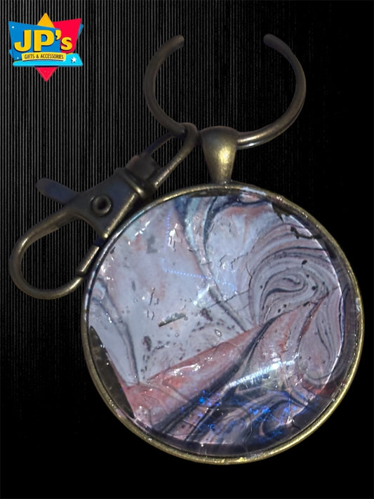 Metal keychain with round glass cabochon featuring abstract swirl pattern in blue, red, white, and gray tones.