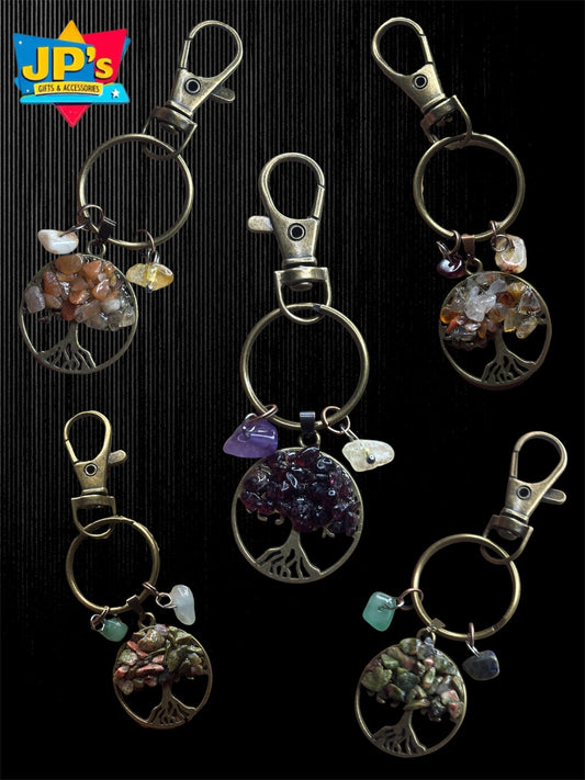 Five Tree of Life keychains with assorted gemstone accents and metal clasps on black background.