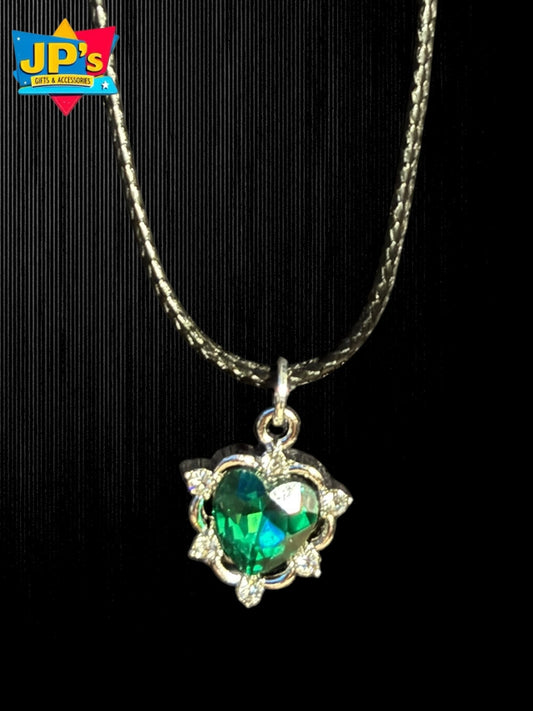 Silver ornate heart necklace with green faceted crystal pendant and decorative spike details on chain.