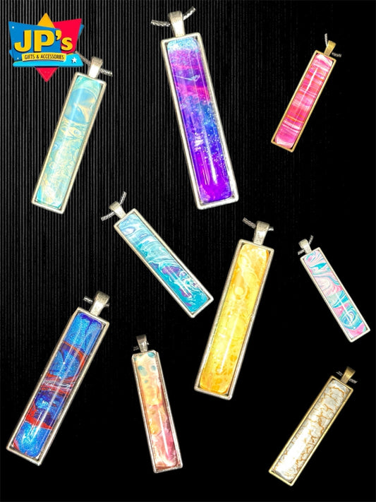 Collection of colorful rectangular resin pendant necklaces with gradient patterns and silver metal bails displayed on black background.