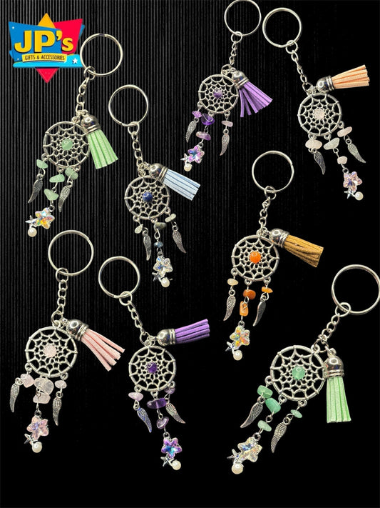 Collection of eight dreamcatcher-style keychains with metal charms, colored beads, feathers, and tassels in various colors.