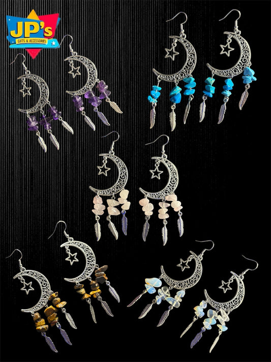 Six pairs of silver moon and star earrings with colorful gemstone and feather dangles in purple, blue, cream, and gold.